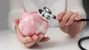 person-putting-stethoscope-piggy-bank